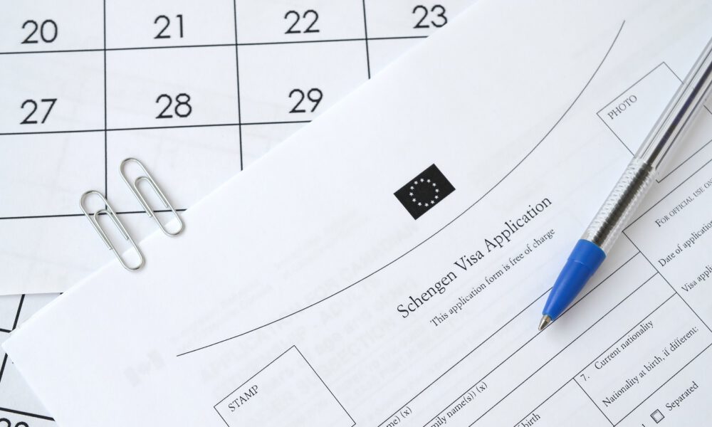 Schengen Visa application form and blue pen on paper calendar page close up